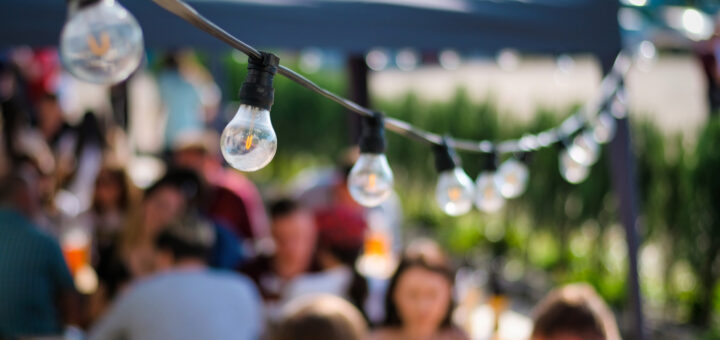 Hanged lamps at outdoor restaurant with multiple visitors on the background, BBQ,